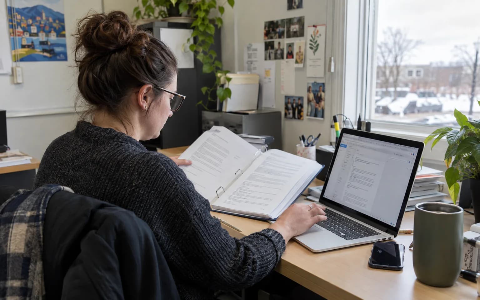 Photo générée par IA : une personne compare un document approuvé à une foire aux questions sur son ordinateur.